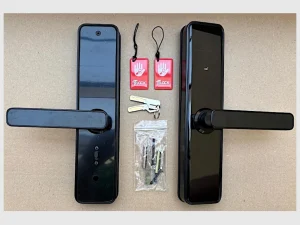 Lieferumfang des schwarzen TTLOCK RENTY mit Innen- und Außeneinheit, zwei mechanischen Schlüsseln, zwei Zugangstranspondern und Montagematerial.